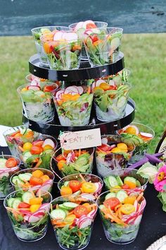 a table topped with lots of salads and cups filled with vegtables