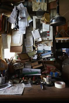 cluttered desk with many papers hanging from the ceiling