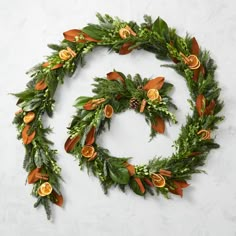 a christmas wreath with oranges and greenery hanging from it's sides on a white wall