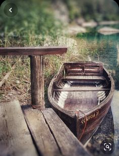 a small boat sitting on top of a wooden dock next to a body of water