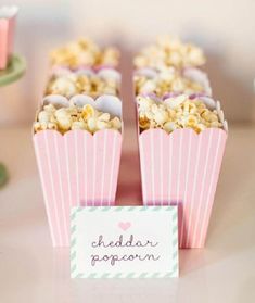 two pink boxes filled with popcorn sitting on top of a table