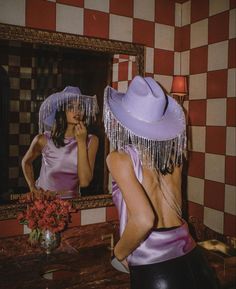 a woman in a purple dress and hat brushing her teeth while looking at herself in the mirror