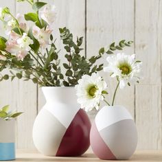 three vases with flowers in them sitting on a table next to each other,