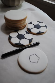 cookies decorated with black and white soccer balls are sitting on a table next to a marker