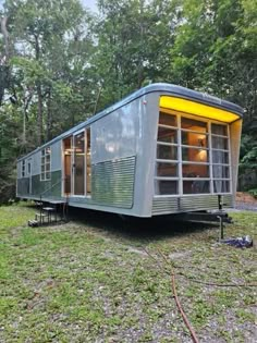 a tiny house sits in the middle of a grassy area with trees and grass around it