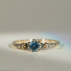 a close up of a ring with a blue stone in it on a white surface