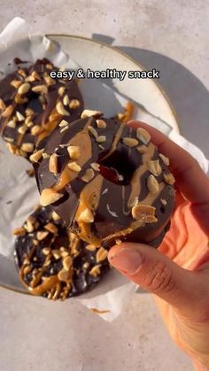 a hand holding a chocolate donut with nuts on it and the words easy & healthy snack