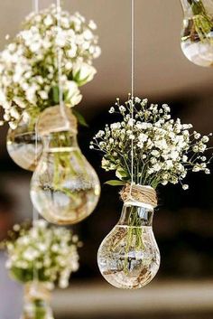 three hanging vases filled with flowers and small white flowers are suspended from the ceiling