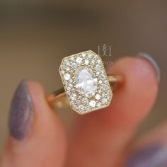 a woman's hand holding an engagement ring with a diamond center in the middle