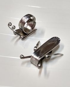 two metal spoons sitting next to each other on top of a white countertop