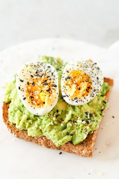 an avocado toast topped with hard boiled eggs and sprinkles on a white plate