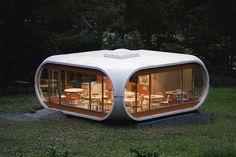 an unusual house in the middle of a grassy area with tables and chairs inside it