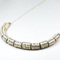 a necklace made out of old books with words written on the front and back, hanging from a silver chain