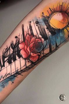 a colorful tattoo with flowers and piano keys on the arm, painted in watercolor