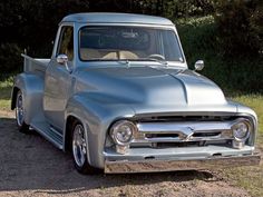 an old silver truck is parked in the dirt