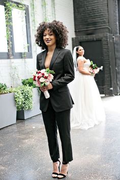 a woman in a black suit holding flowers