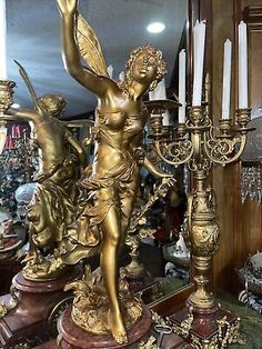 an antique brass figurine is on display in a store with candles and other items