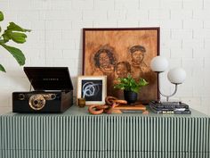 a table topped with an old fashioned record player and other items next to a painting