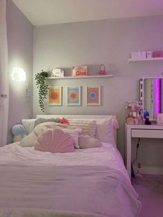 a white bed sitting under a purple light in a bedroom