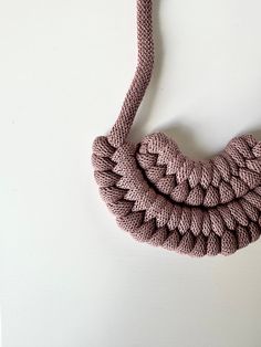 a pink necklace is hanging on a white wall