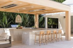 an outdoor kitchen with bar seating and lots of greenery