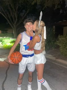 a man and woman dressed up as basketball players kissing on the cheek while standing next to each other