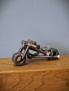 a pair of metal scissors sitting on top of a wooden table next to a blue wall