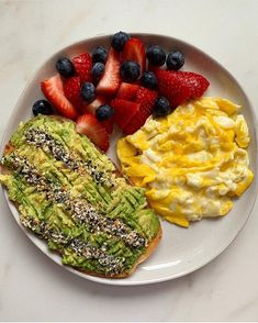 an avocado toast, scrambled eggs and strawberries on a plate