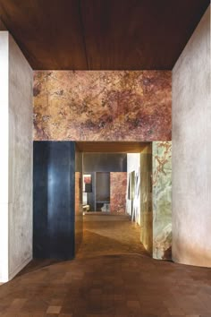 an empty room with wood flooring and marble walls on either side of the hallway