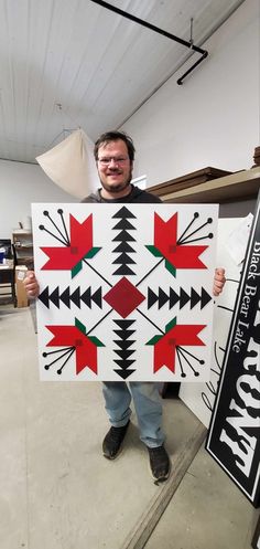 a man holding up a large piece of art with arrows on the front and sides