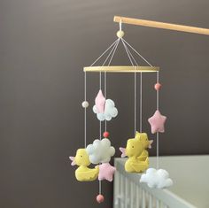 a baby crib mobile with clouds and stars hanging from it's sides in a nursery room