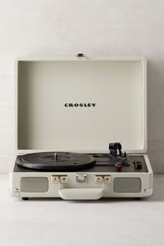 an old fashioned record player sitting in a white case with the word crosley on it