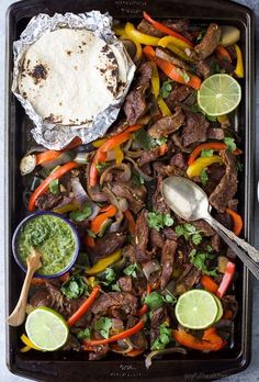 a tray filled with meat and vegetables next to a tortilla