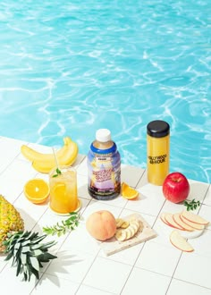 an assortment of fruit sitting on the edge of a pool next to a pineapple