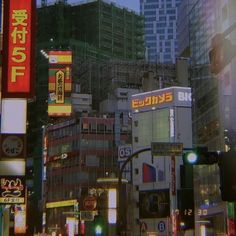 a city street filled with lots of tall buildings and traffic lights at night time in tokyo, japan