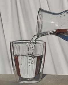 a glass filled with water being poured into it