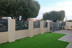 a fenced in area with artificial grass and trees