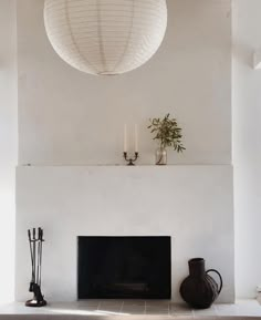 a living room with a fire place and vases on the mantel above it