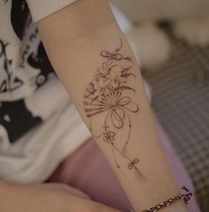 a woman with a tattoo on her arm holding onto a small wristband that has flowers in it