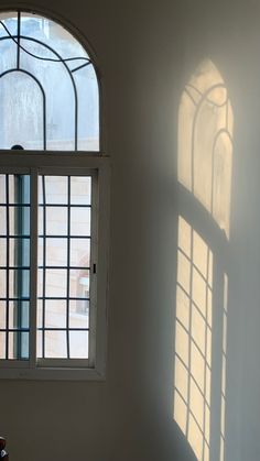 an open window in a white room with sunlight coming through the windows and casting shadows on the wall