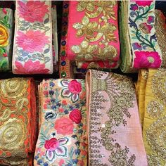 many different types of fabrics are on display in a store window, with gold sequins and flowers all over them