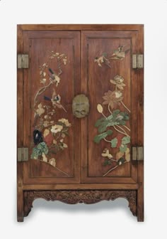 an old wooden cabinet with flowers and birds on the doors, decorated with metal hardware