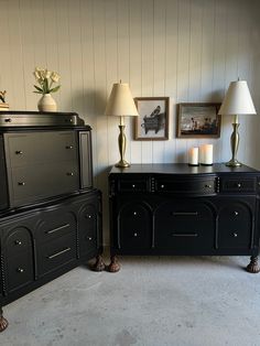 two lamps are sitting on top of black dressers in a room with white walls