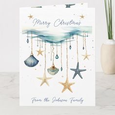 a christmas card with seashells and starfish hanging from the strings on it