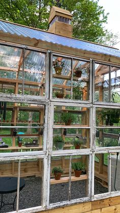 an old greenhouse with lots of plants growing in the glass walls and windows on each side