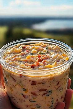 a hand holding a glass container filled with food