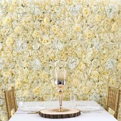 the table is set with two champagne glasses and place settings, along with floral wallpaper