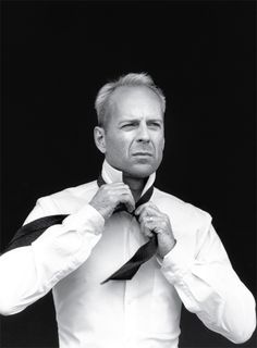 a black and white photo of a man adjusting his tie