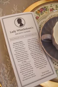 a tea cup and saucer sitting on top of a table next to a menu