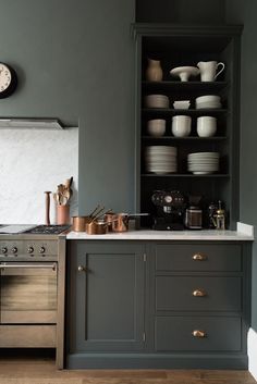 a kitchen with gray cabinets and white plates on the counter top, along with an oven